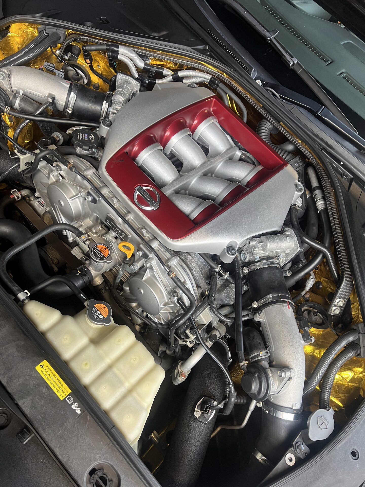 Nissan GT-R VR38 engine bay fully detailed by Auto-Glo with gold heat shield and clean cam covers